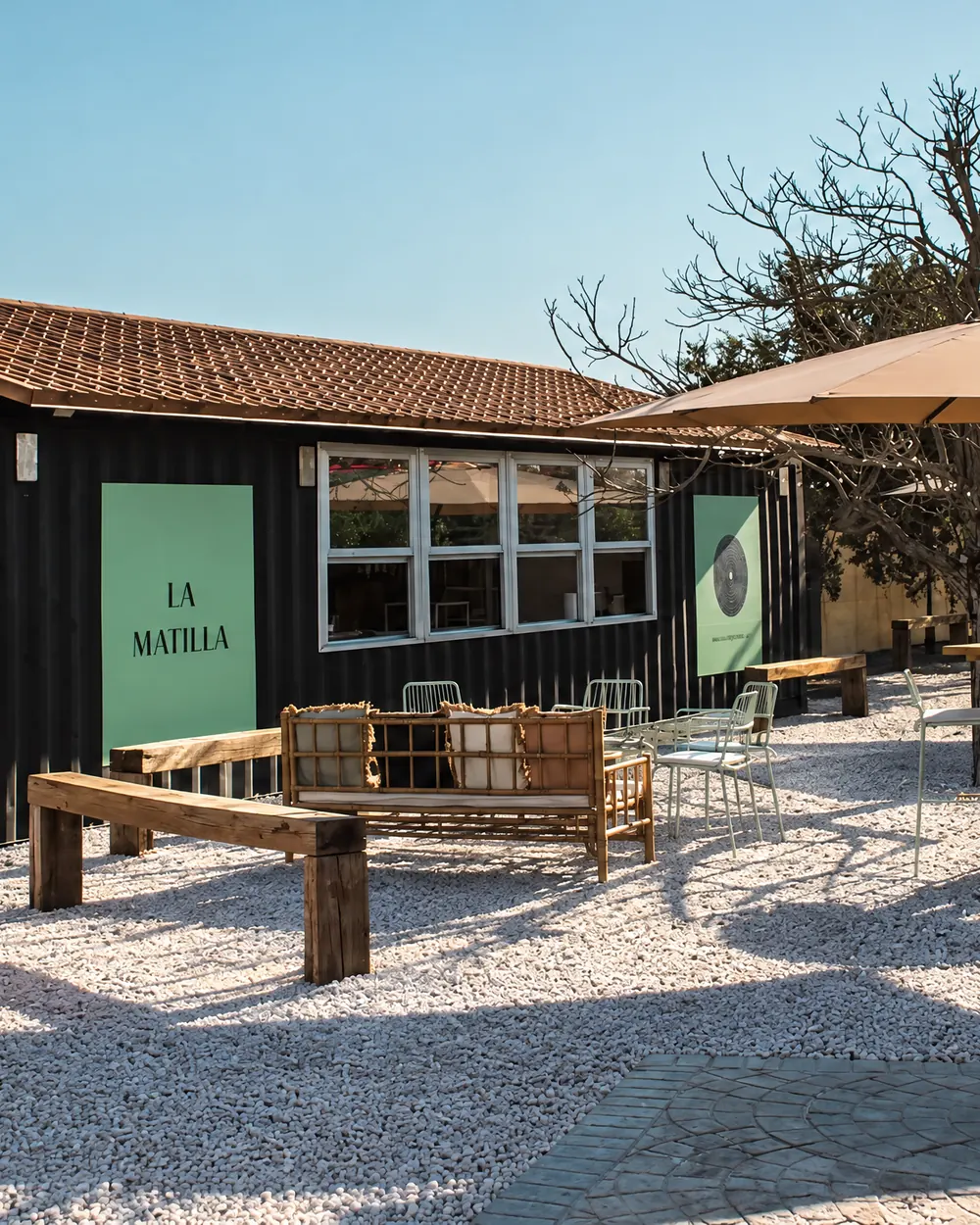 El Container: terraza con sofás de bambú y mesas de madera sobre chinos blancos