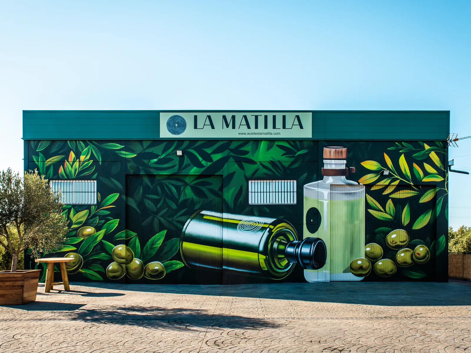 Nave de La Matilla con el mural de olivos, aceitunas y botellas de aceite