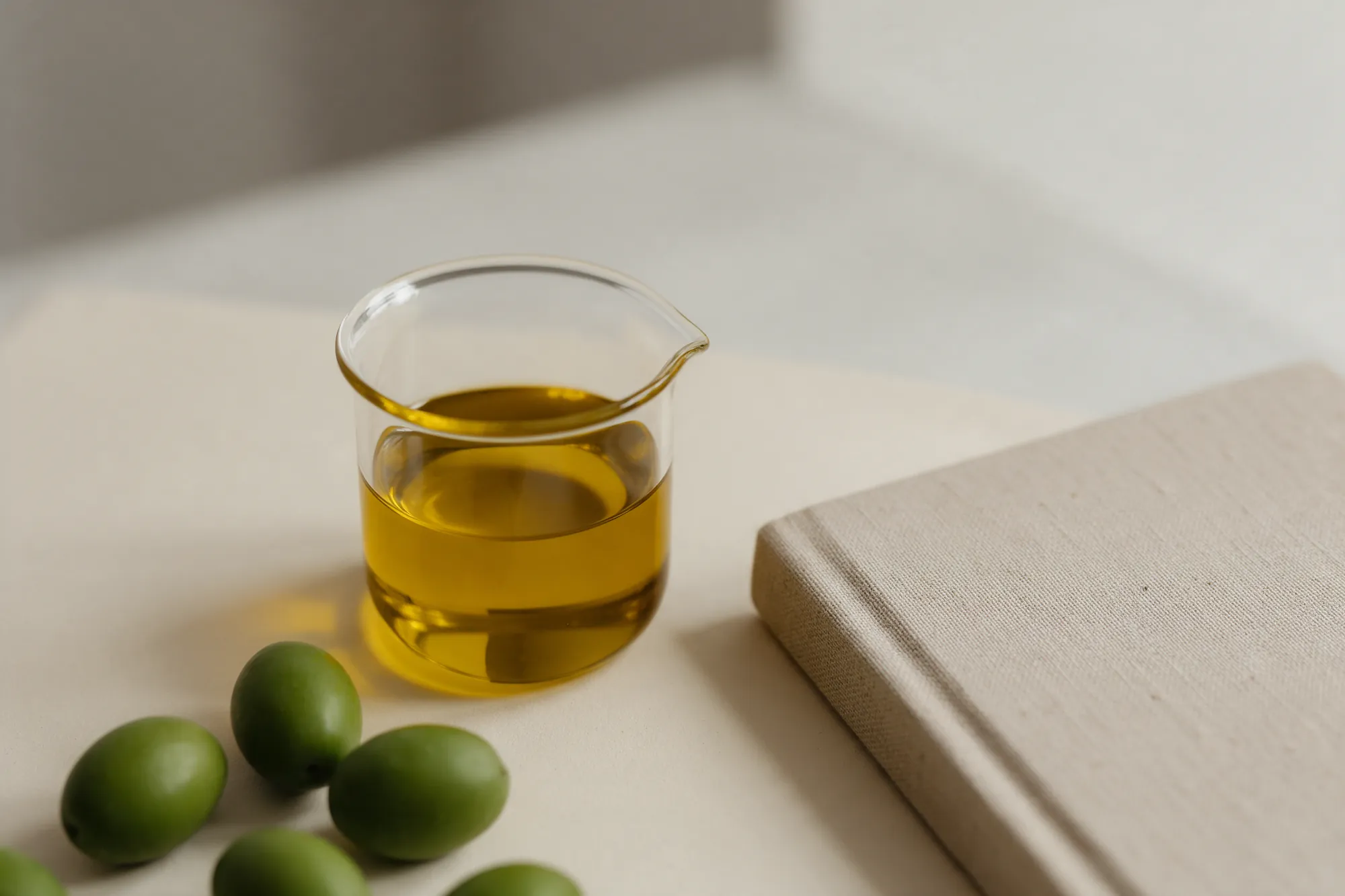 Aceite en vaso de cristal junto a aceitunas